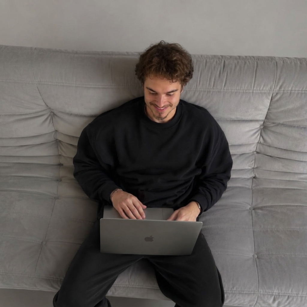 Guillem Canudas, Co-Founder of Cala Creative, working on a laptop on a gray sofa