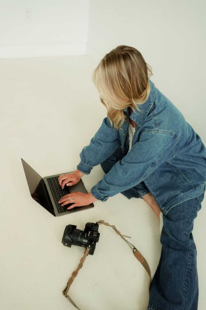 Creative content creator sitting on the floor working on a laptop with a professional camera nearby